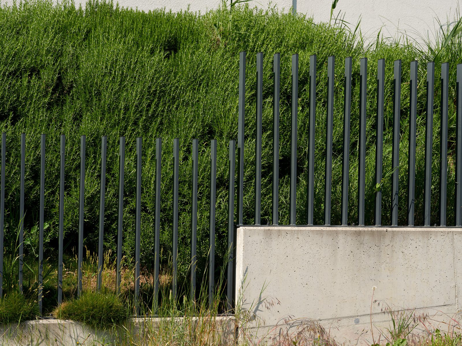 Stabzaun aus Stahl auf Betonsockel entlang eines Hangs, gefertigt von der Schlosserei Bierbaumer