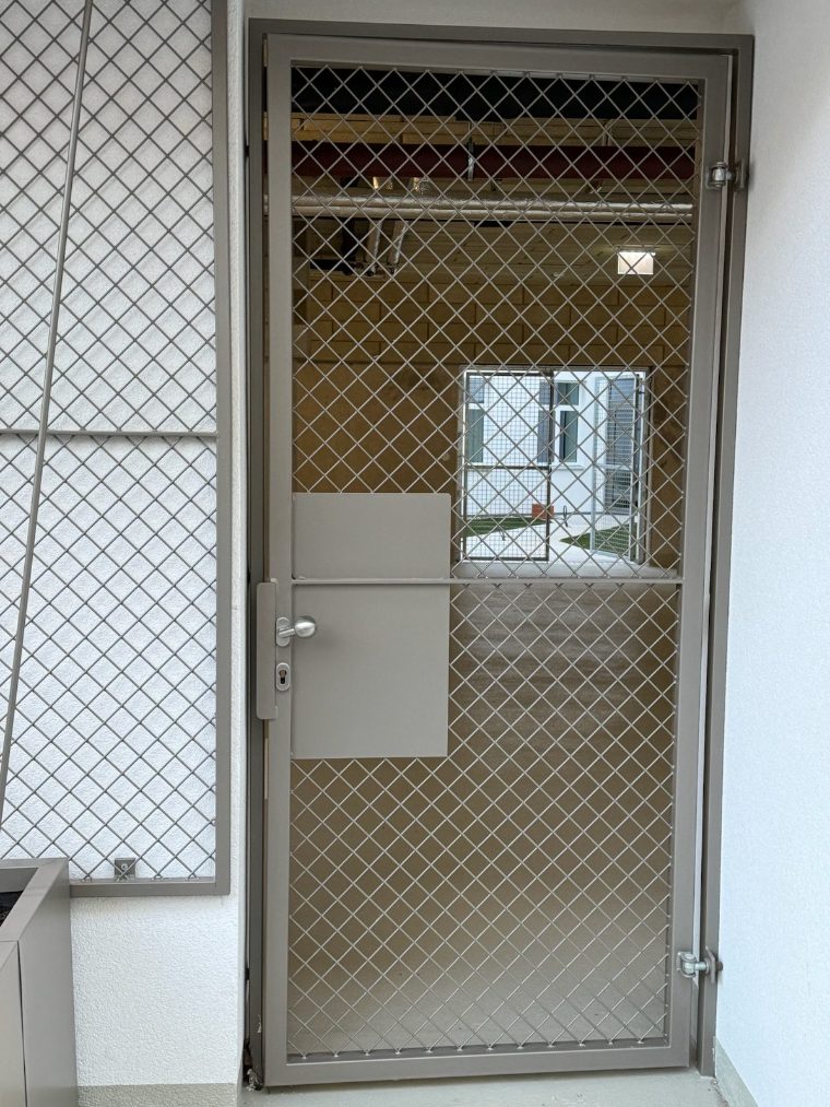 Gittertür aus Metallgewebe an einem Nebenraum