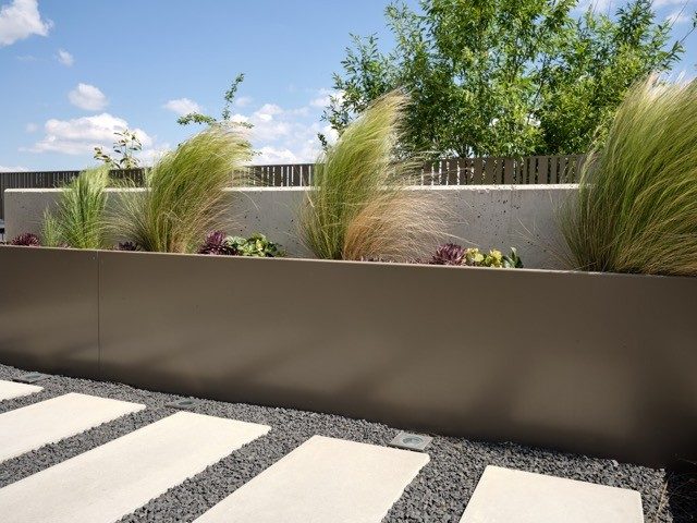 Langer Pflanztrog aus Metall mit Ziergräsern auf einer Dachterrasse