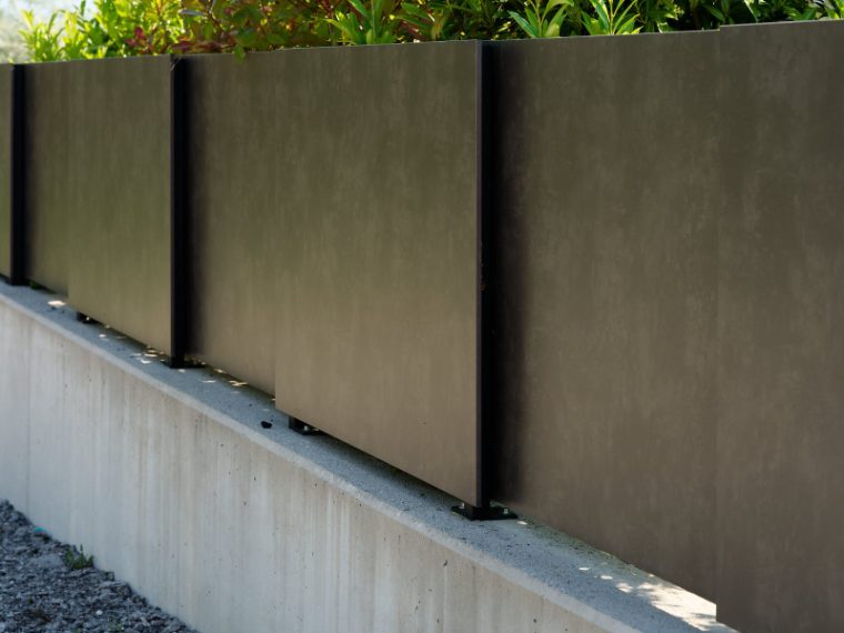 Sichtschutzwände aus Metall auf einer Betonmauer