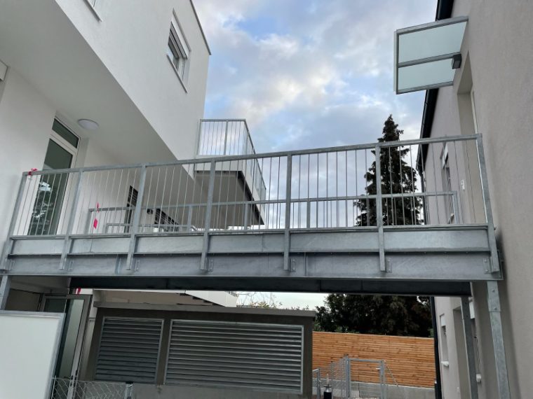 Stahlsteg mit Geländer zwischen zwei Gebäudeteilen