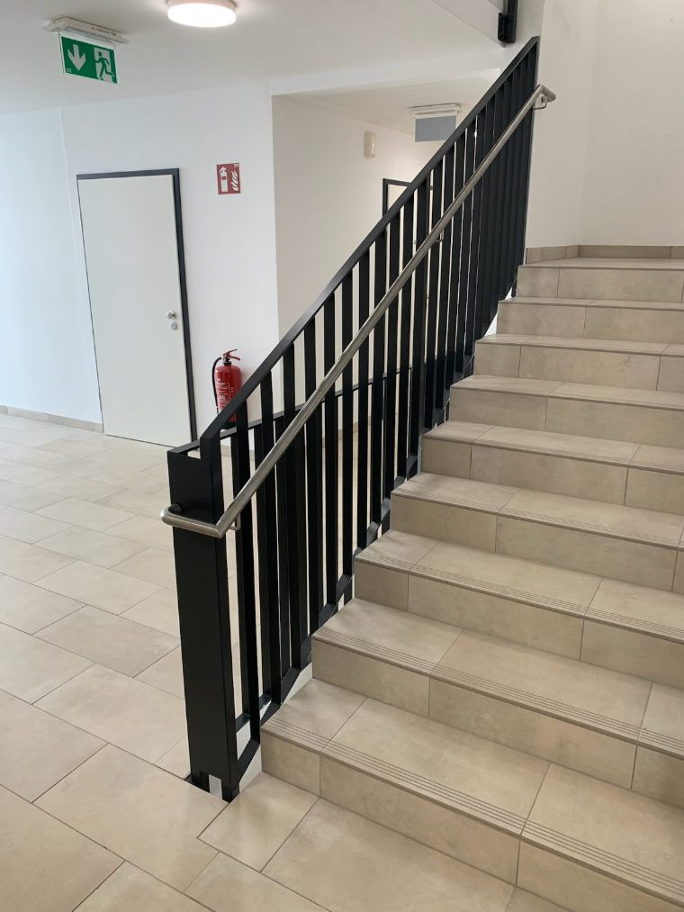 Stiegenhaus mit schwarzem Geländer und Handlauf