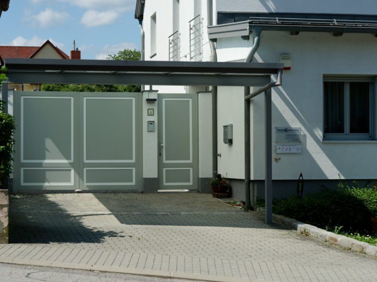 Stahlvordach über einer Einfahrt mit Tor und Nebentür