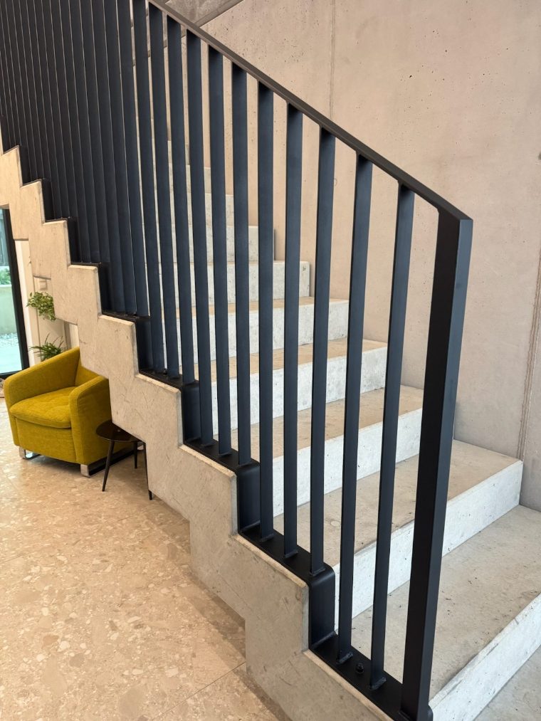 Schwarzes Stahlgeländer an einer Betonstiege im Wohnraum