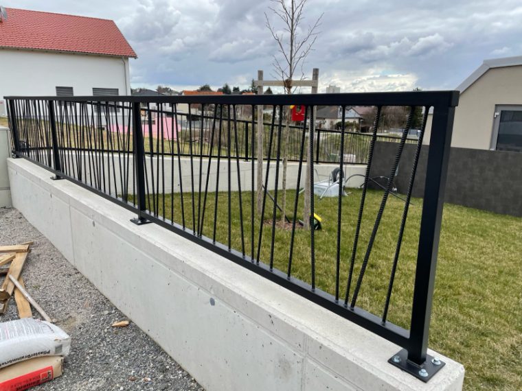 Schwarzer Metallzaun auf einem Betonsockel