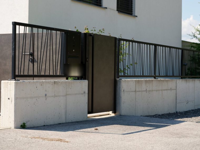 Dunkle Gehtür mit Briefkasten- und Klingelanlage in einer Zaunanlage